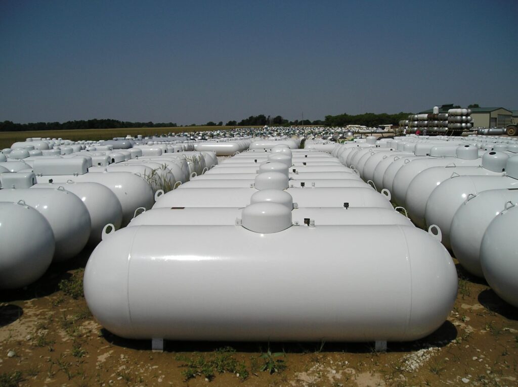 Rows of white horizontal propane tanks with dome caps in a storage yard