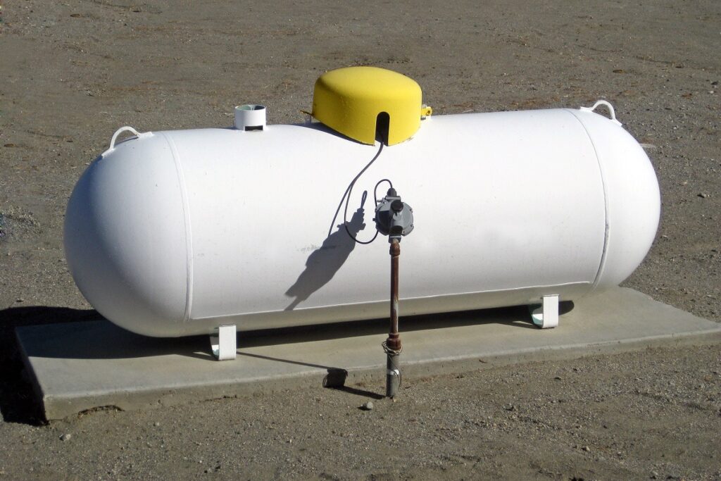 White horizontal propane tank on a concrete pad with a yellow dome cap