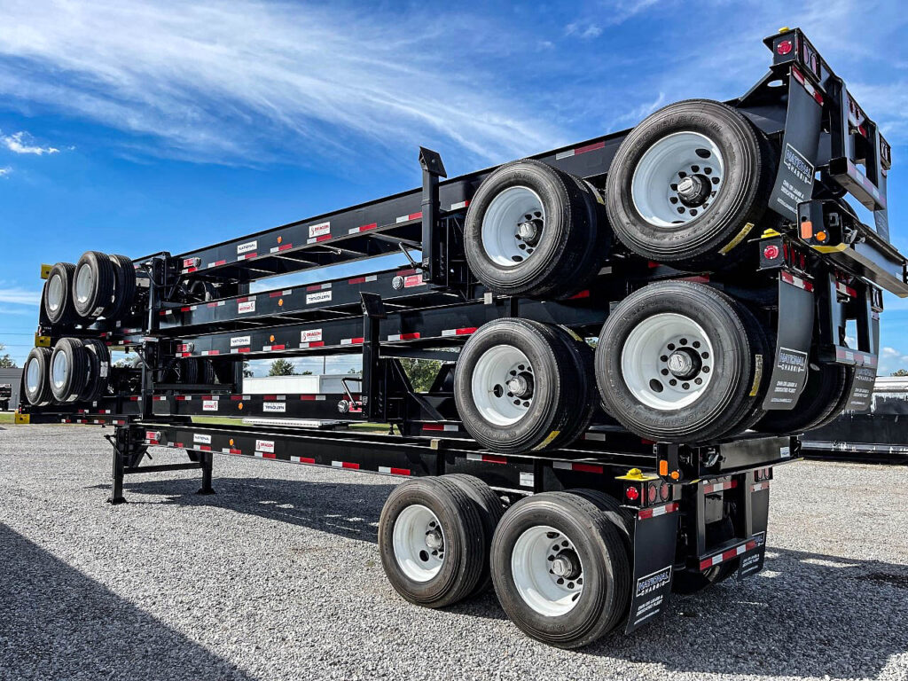 Black container chassis frames stacked with their wheels visible in a yard