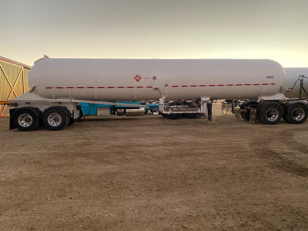 White pressurized LPG tank trailer parked on a gravel lot